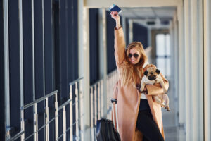 Woman at the airport terminal traveling with her dog during international pet relocation to Paris